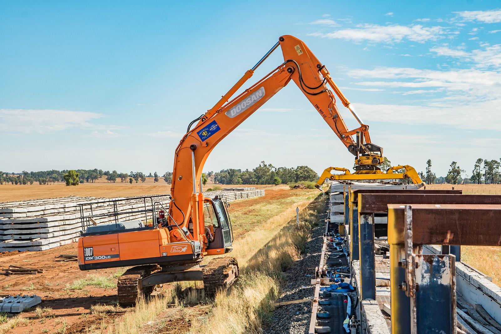 Heavy machinery off loading culverts from a train.