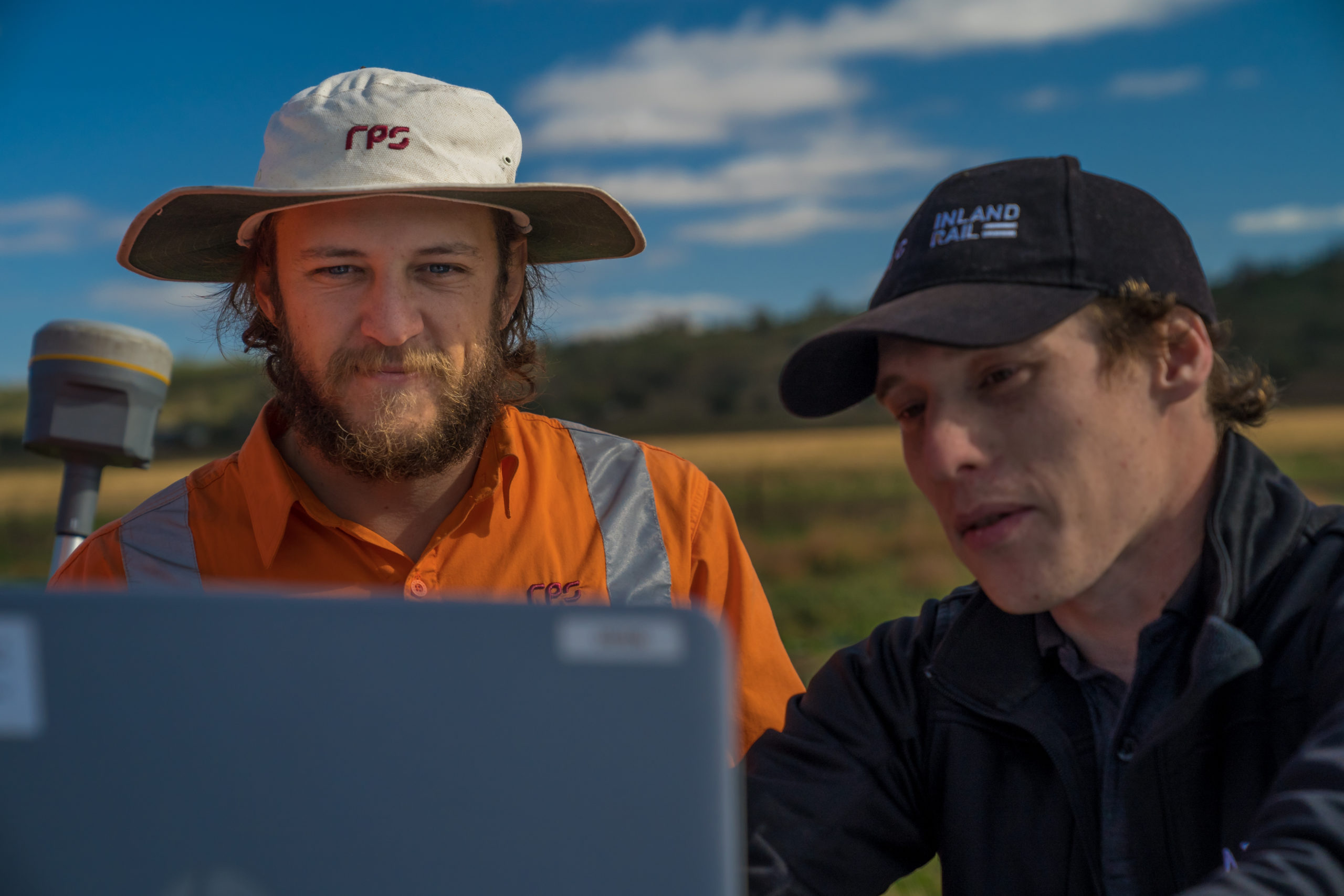 Two Inland Rail employees out in the field looking at results on a laptop.