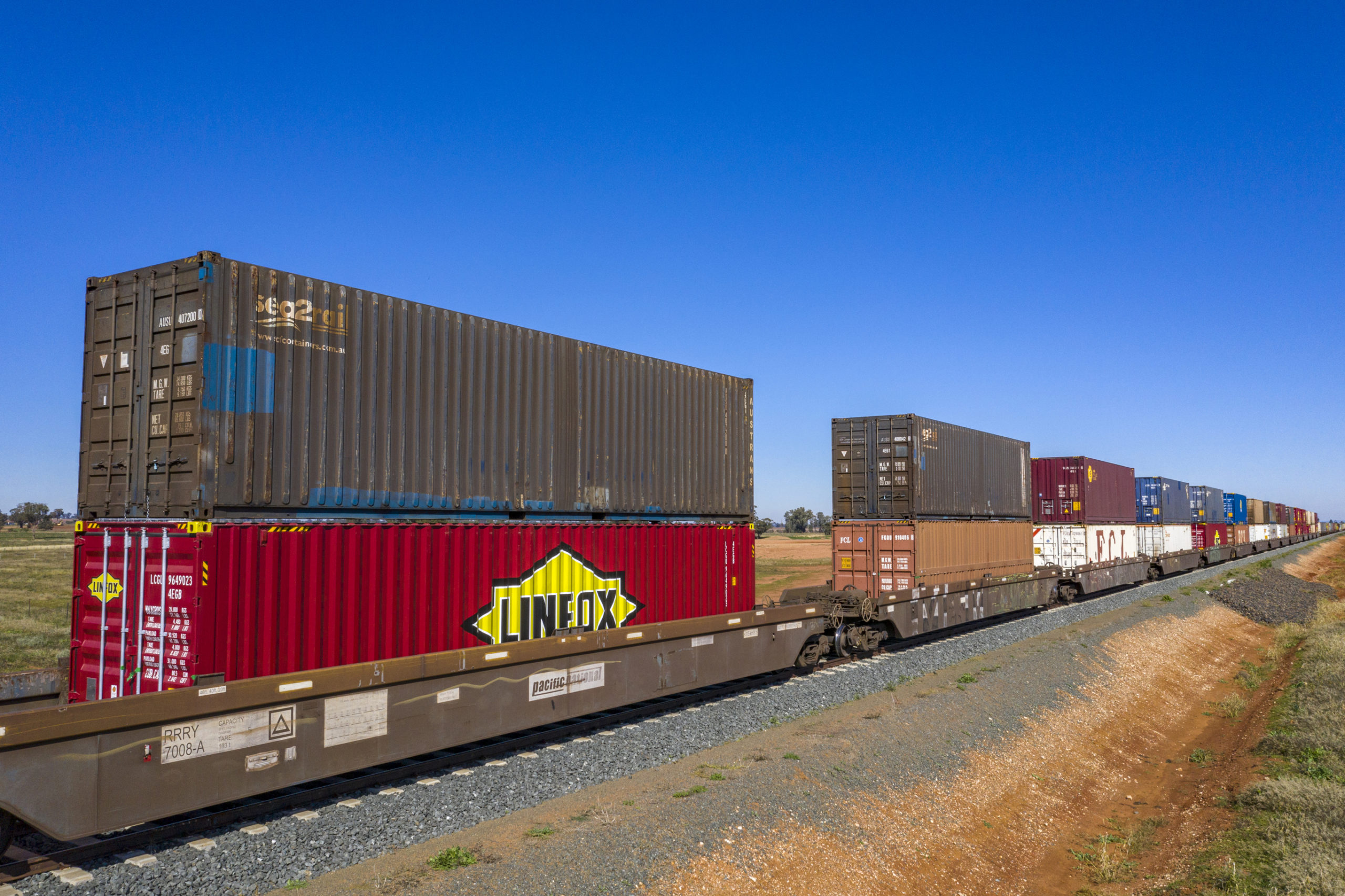 Double-stack container train travels through a rural area near Parkes, New South Wales.