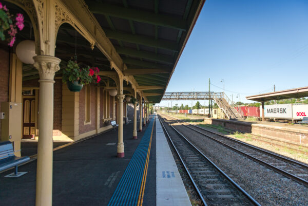A train station platform with a pedestrian footbridge at the end of it.