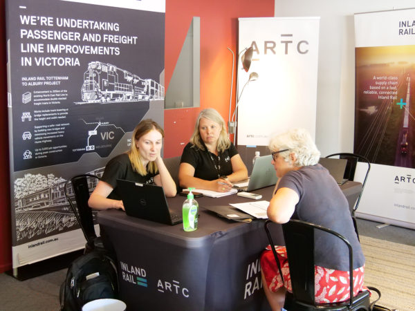 Two Inland Rail employees meeting with a stakeholder and looking at the computer
