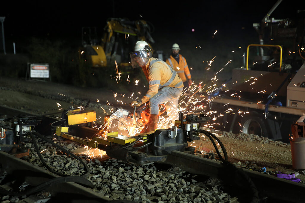 Worker saw cutting a section of the Tycannah crossing loop mainline to create a gap for the destressing process to occur.