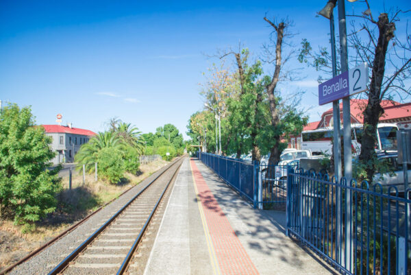 A train station platform stretches into the distance, a car park on one side and a hotel on the other.