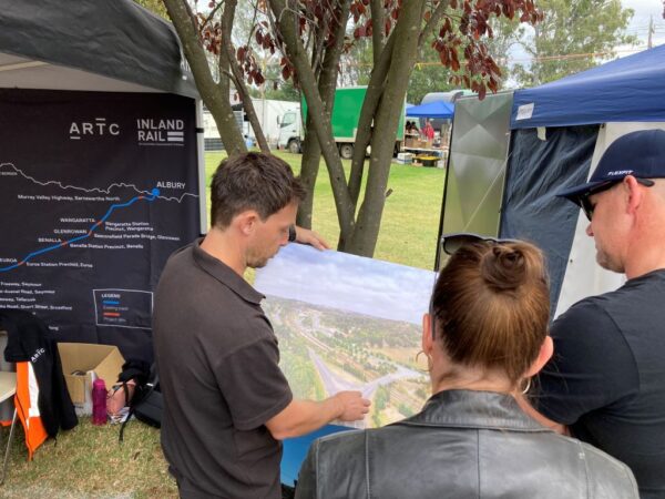 Three people look at an Inland Rail visualisation.