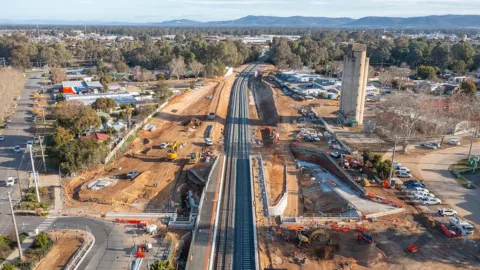 A construction site with a railway line running through the middle of it, in a township.