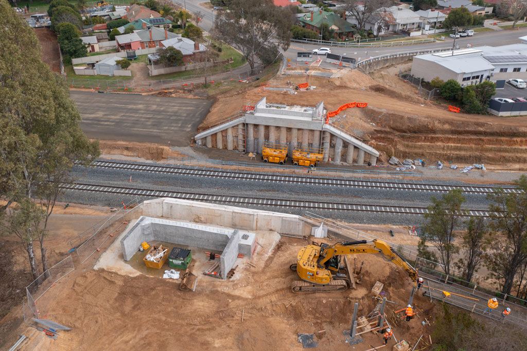 Two railway tracks run through a construction site, with concrete structures on both sides of the tracks.