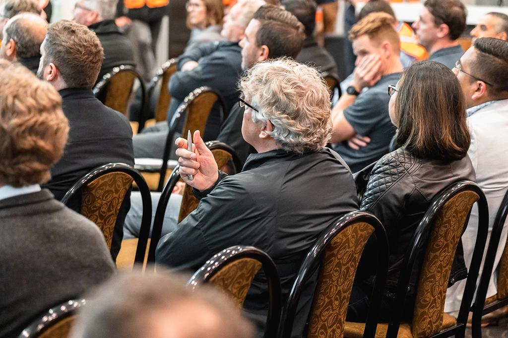 People sitting on chairs in room listening to a lecture.