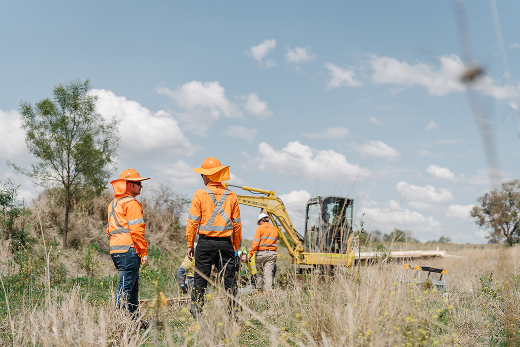 Five workers in high visibility workwear near a piece of machinery