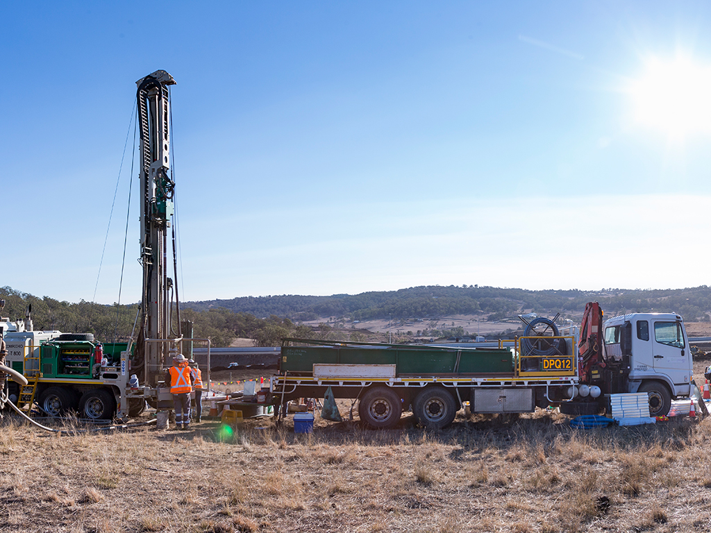 A drill rig and support vehicles set up to dig boreholes.