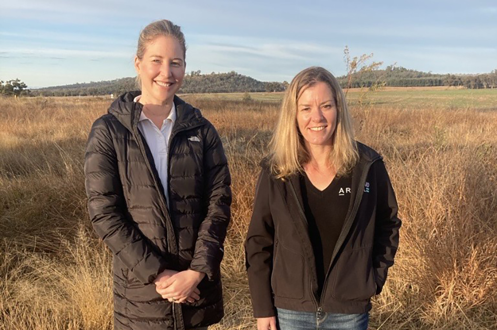 Two smiling women standing in a field