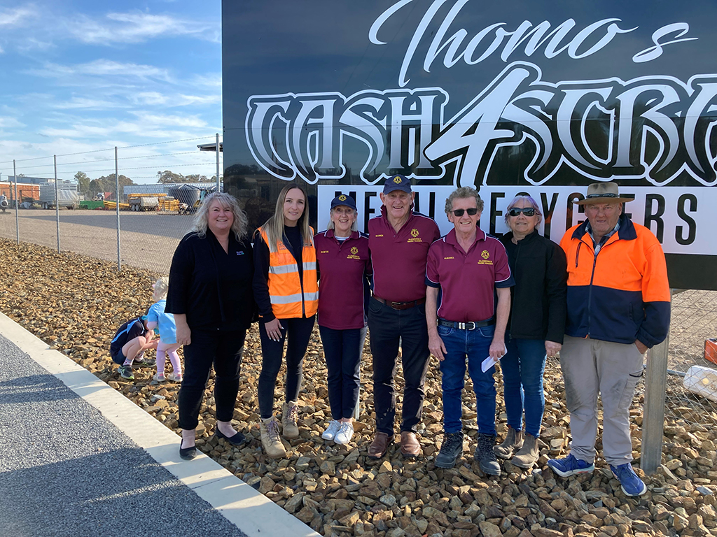 A row of people standing in front of a business sign. 