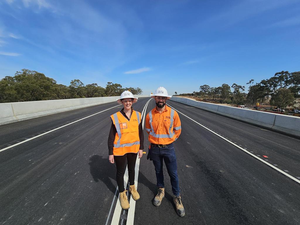 A man and a woman wearing hi-viz PPE workwear standing on a new bridge