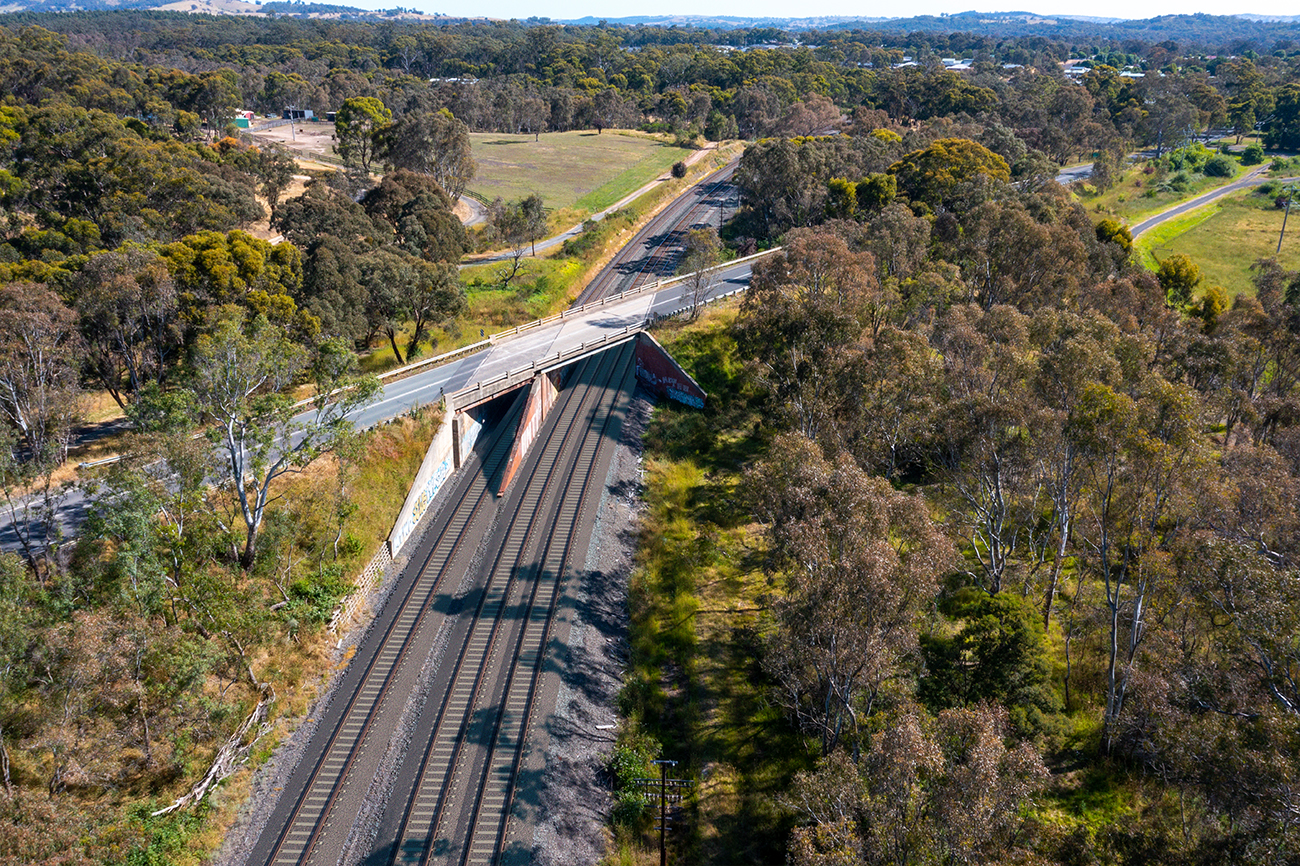 A bridge crosses a rail line in a rural setting.