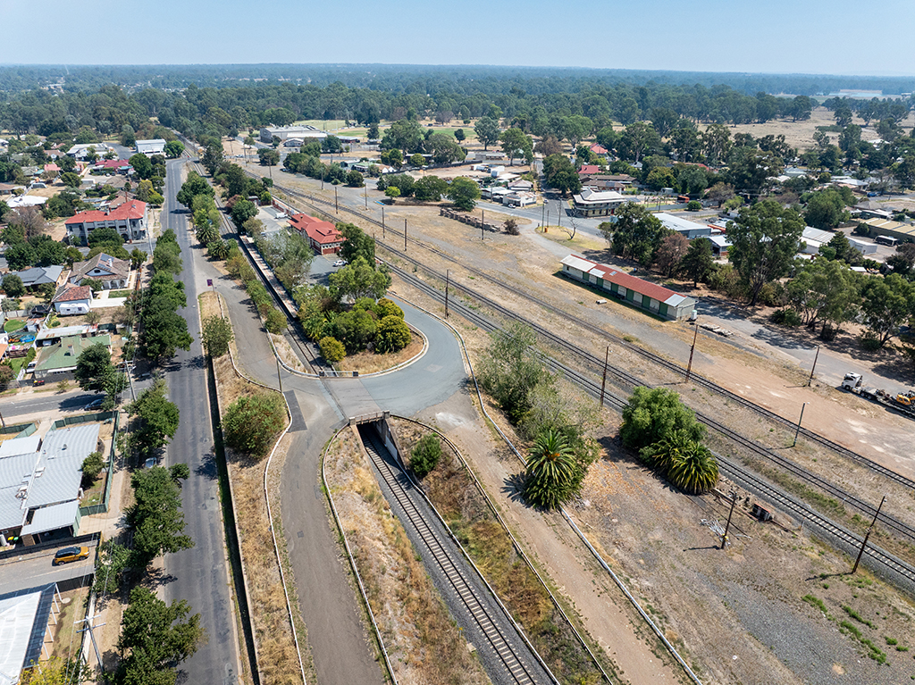 Aerial shot of a road bridge over a rail line with rural town surrounding