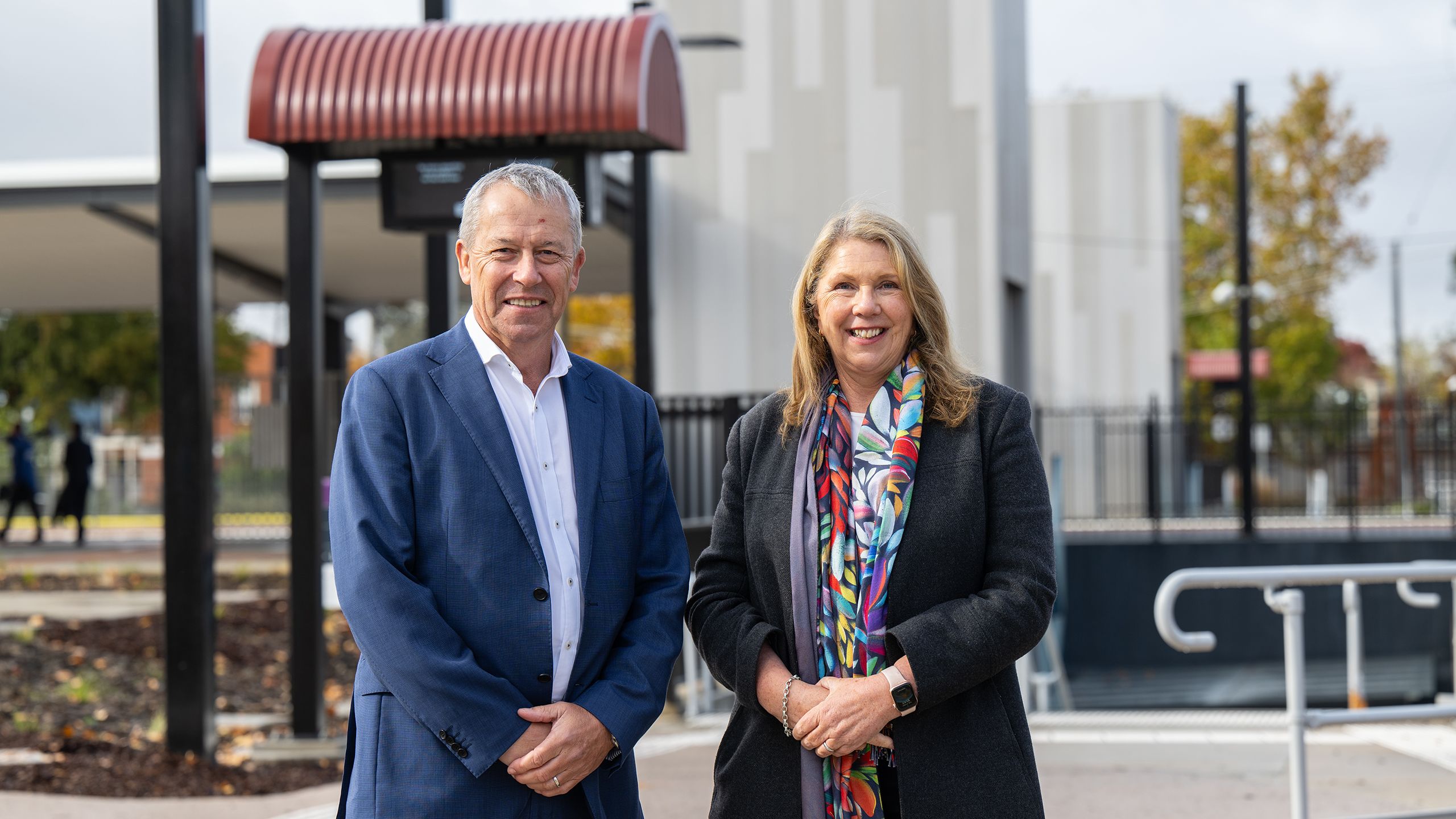 A man and a woman smiling at the camera at a railway station