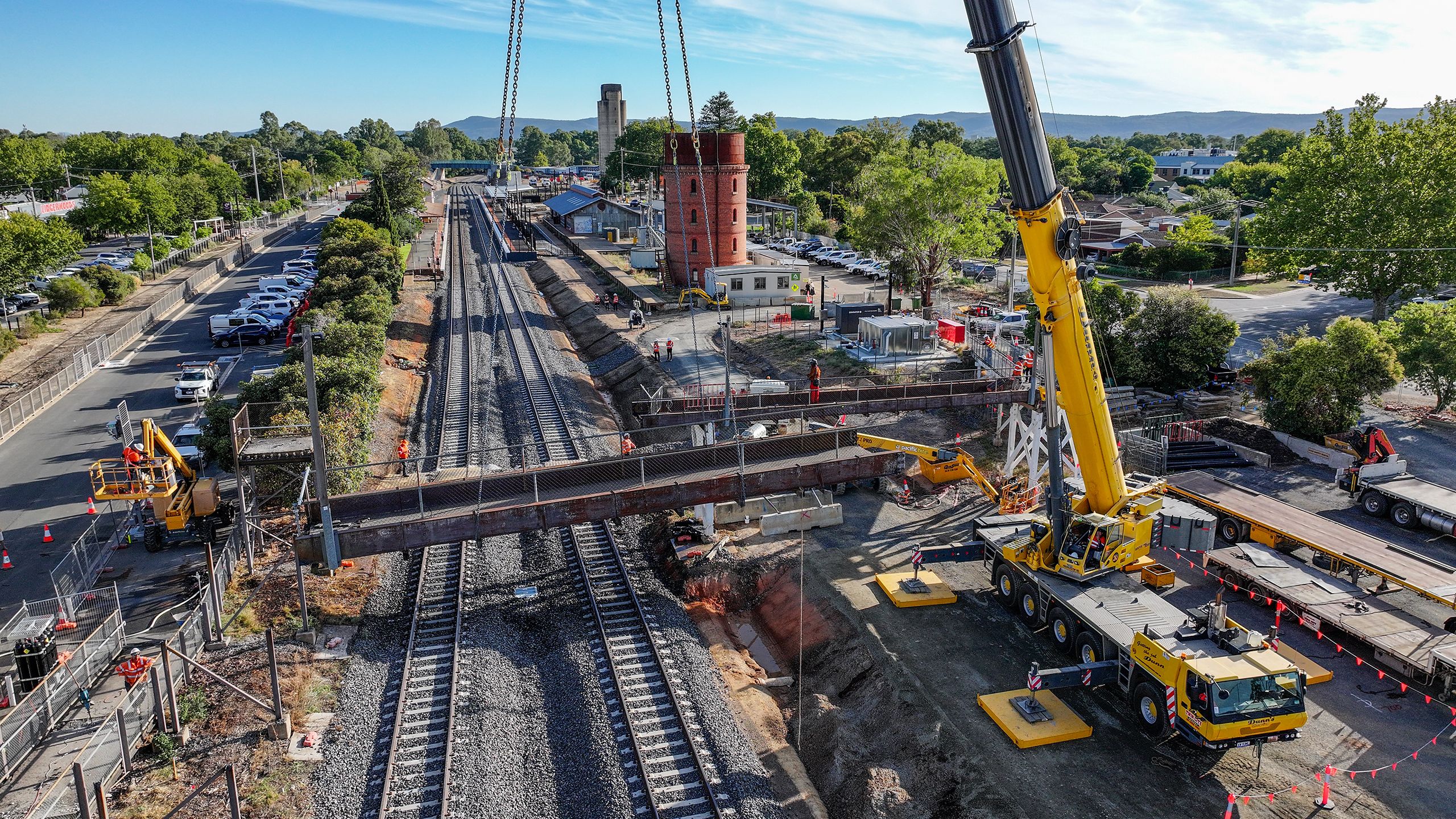 Construction worksite showing a bridge suspended by a crane