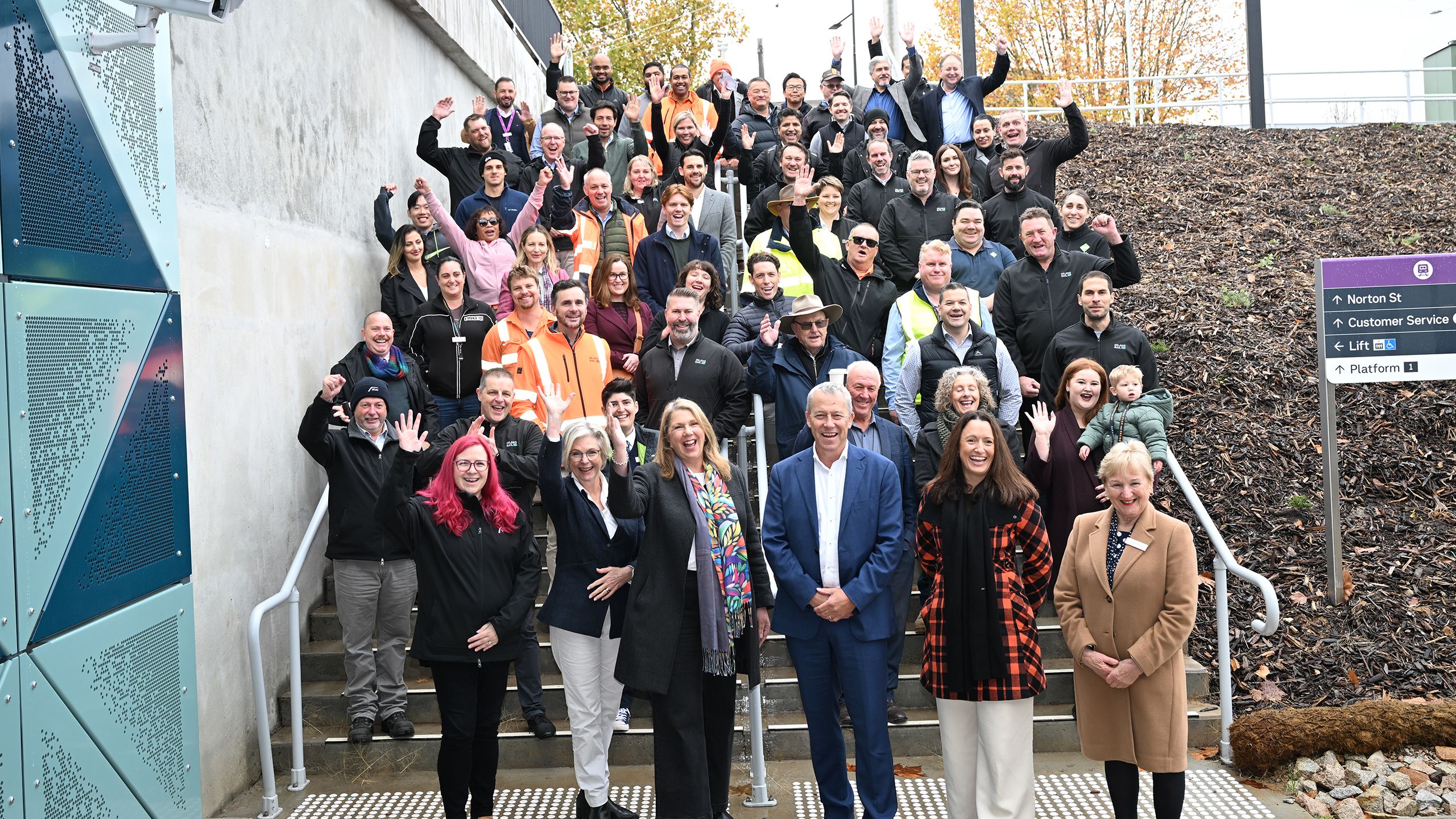A groupe of people standing on steps smiling and some with hands in the air