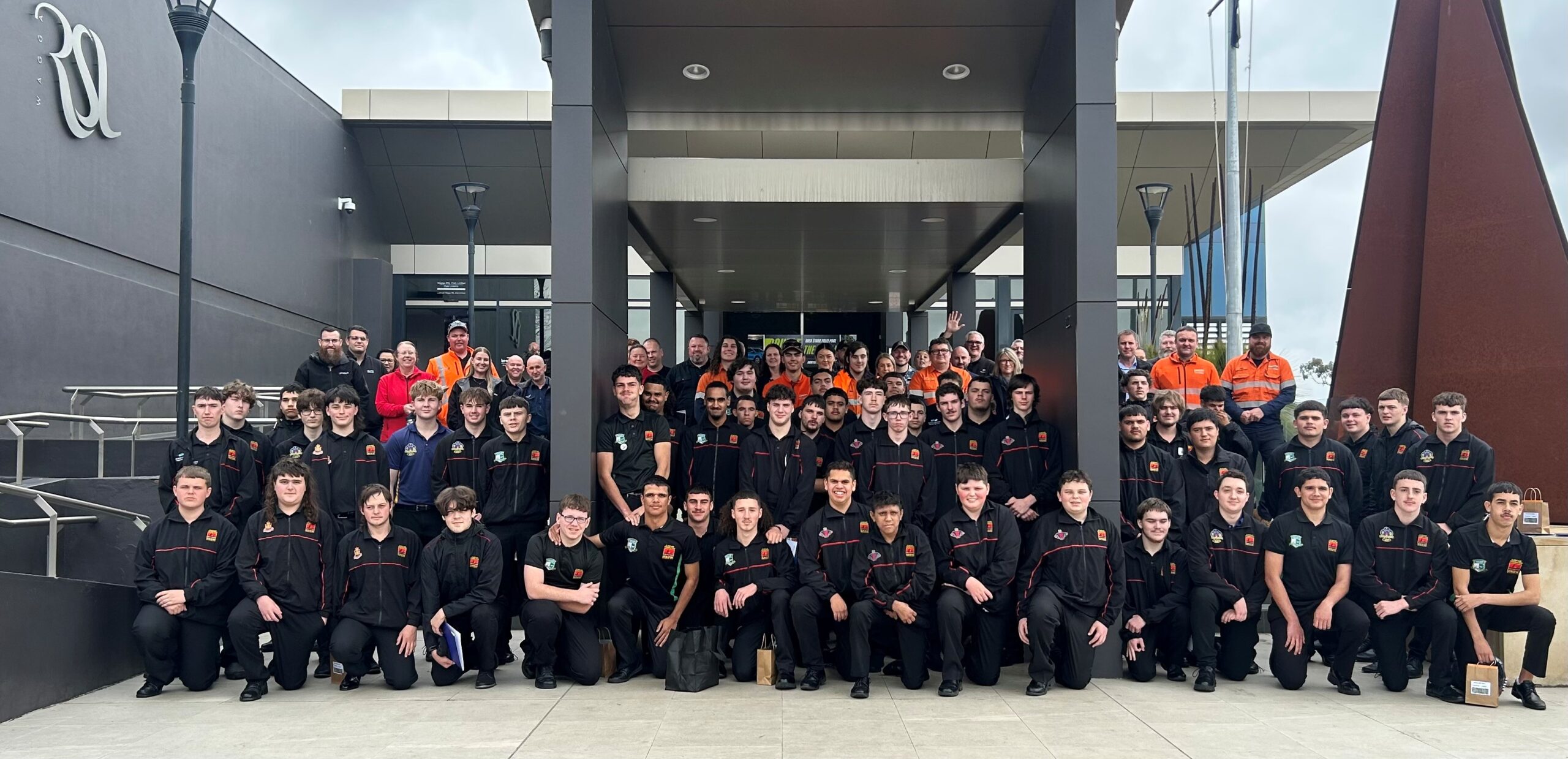 Group of people in front of building sitting for a photo