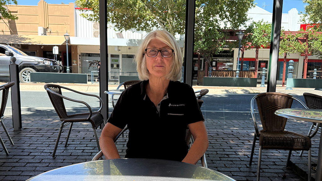 Owner of a Benalla bakery seated at an outdoor café table on a local street.