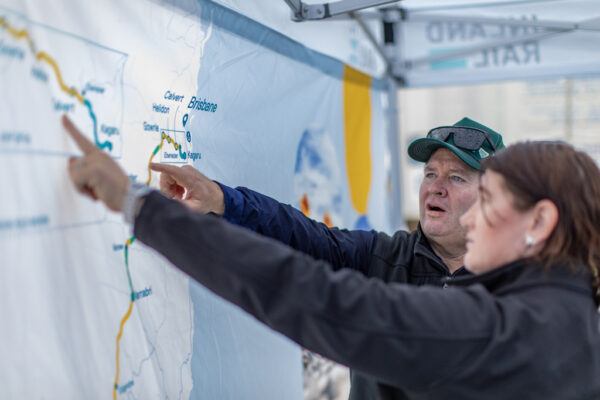 Two people point to a map of Inland Rail that's on a screen.