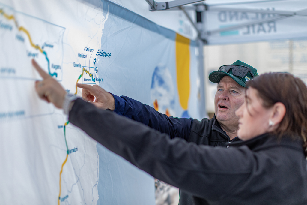 Two people point to a map of Inland Rail that's on a screen.