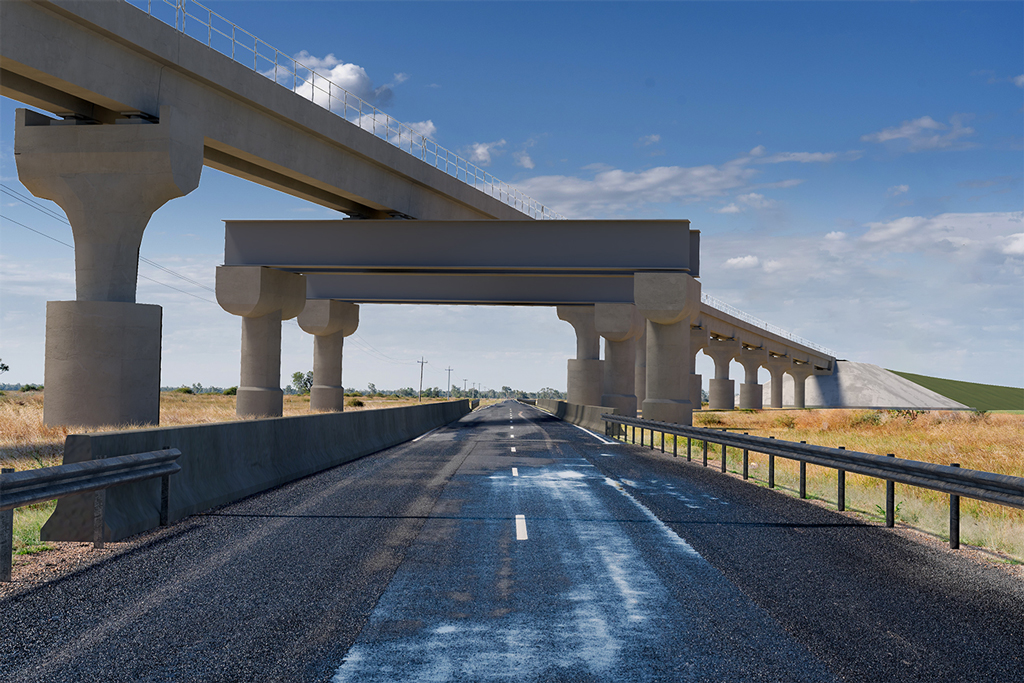 A road in a rural area runs perpendicular to a rail bridge over the road. The bridge starts at an embankment, and extends diagonally across the road at a height.