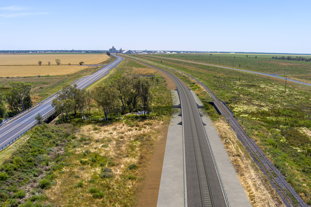 Two rail lines and a road extend into the horizon ina rural area.