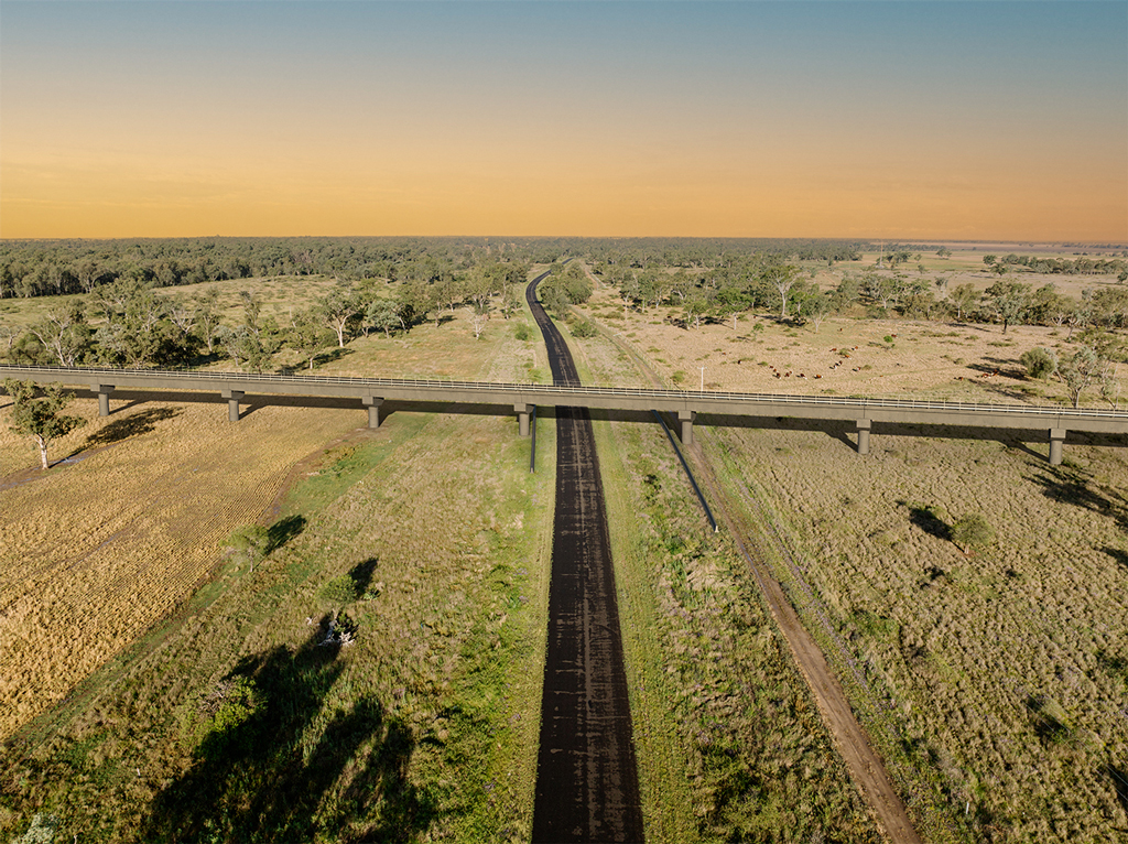 A rural scene where a road and a rail line run into the horizon.