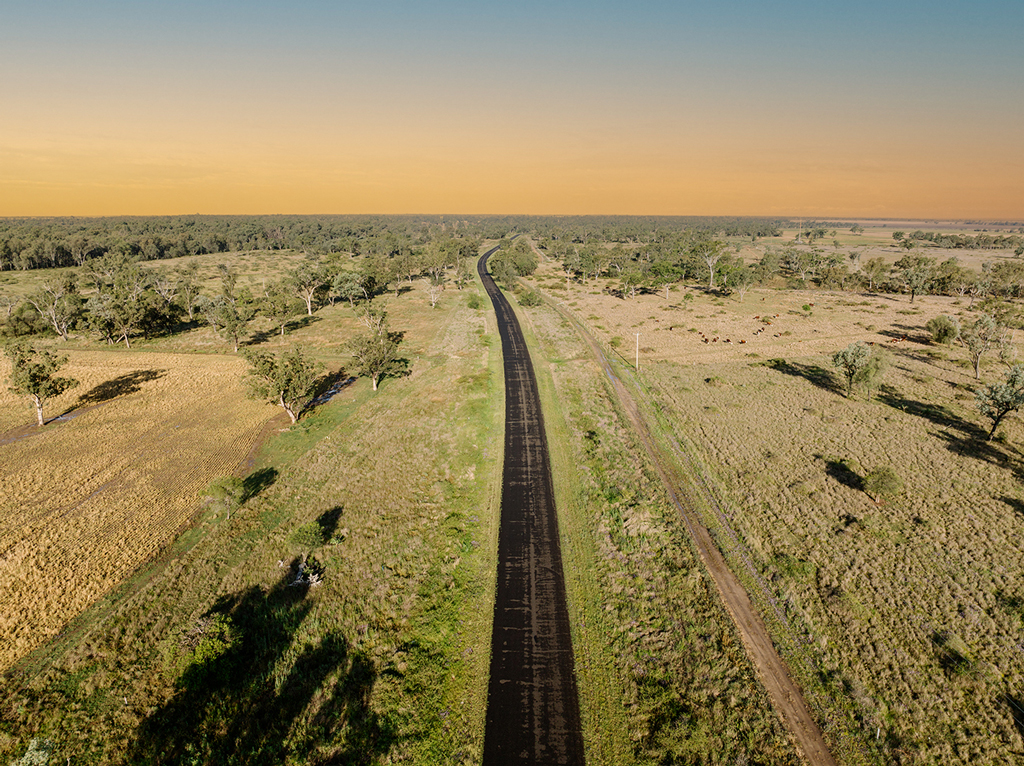 A rural scene where a road and a rail line run into the horizon.