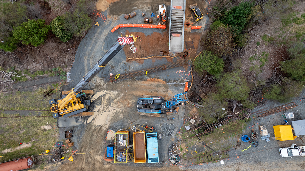 Aerial view of machinery and equipment set up beside rail tracks at a work site.
