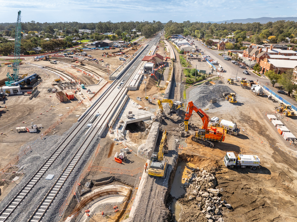 A train station and railway tracks sit next to a busy construction site.