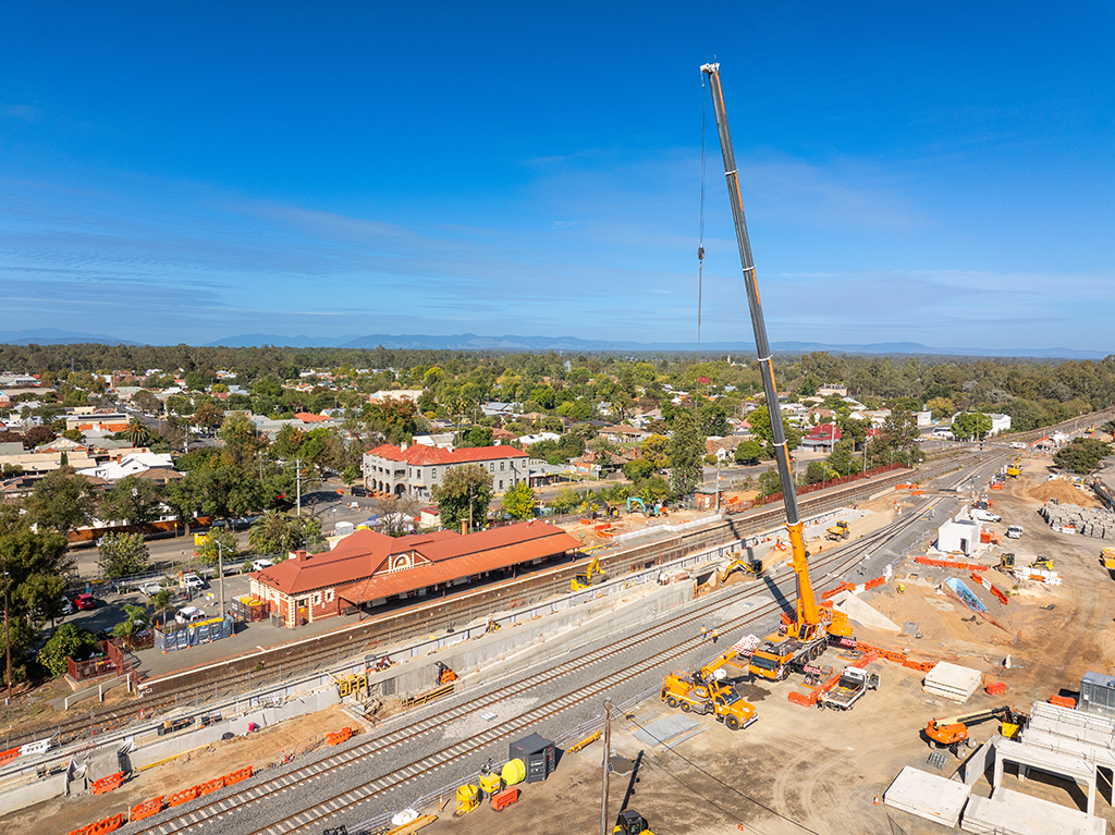 Aerial view of rail works through a town, with cranes, machinery and station buildings visible.