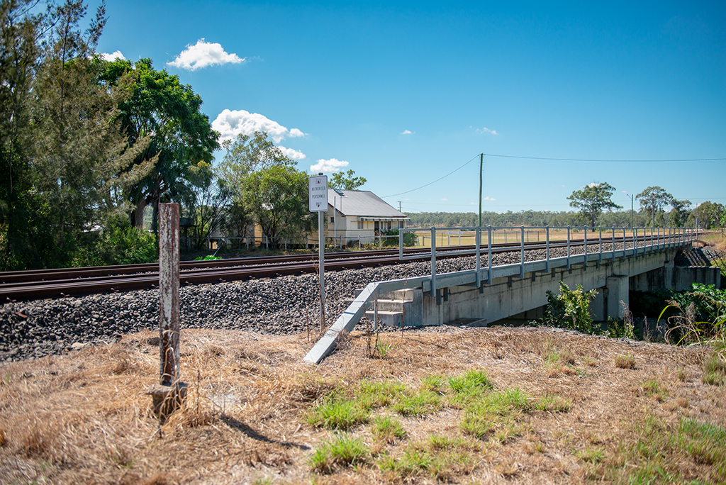 A railway bridge with a small house behind it, in a rural area.