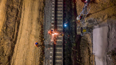 A worker uses a cutting tool on a piece of railway track