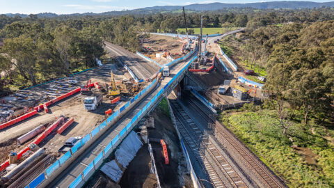Drone aerial view of a bridge over railway tracks with construction equipment.