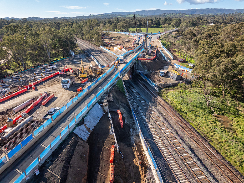 Drone aerial view of a bridge over railway tracks with construction equipment.