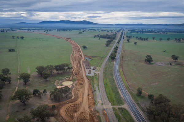 Aerial view of a cleared construction corridor running alongside a highway.